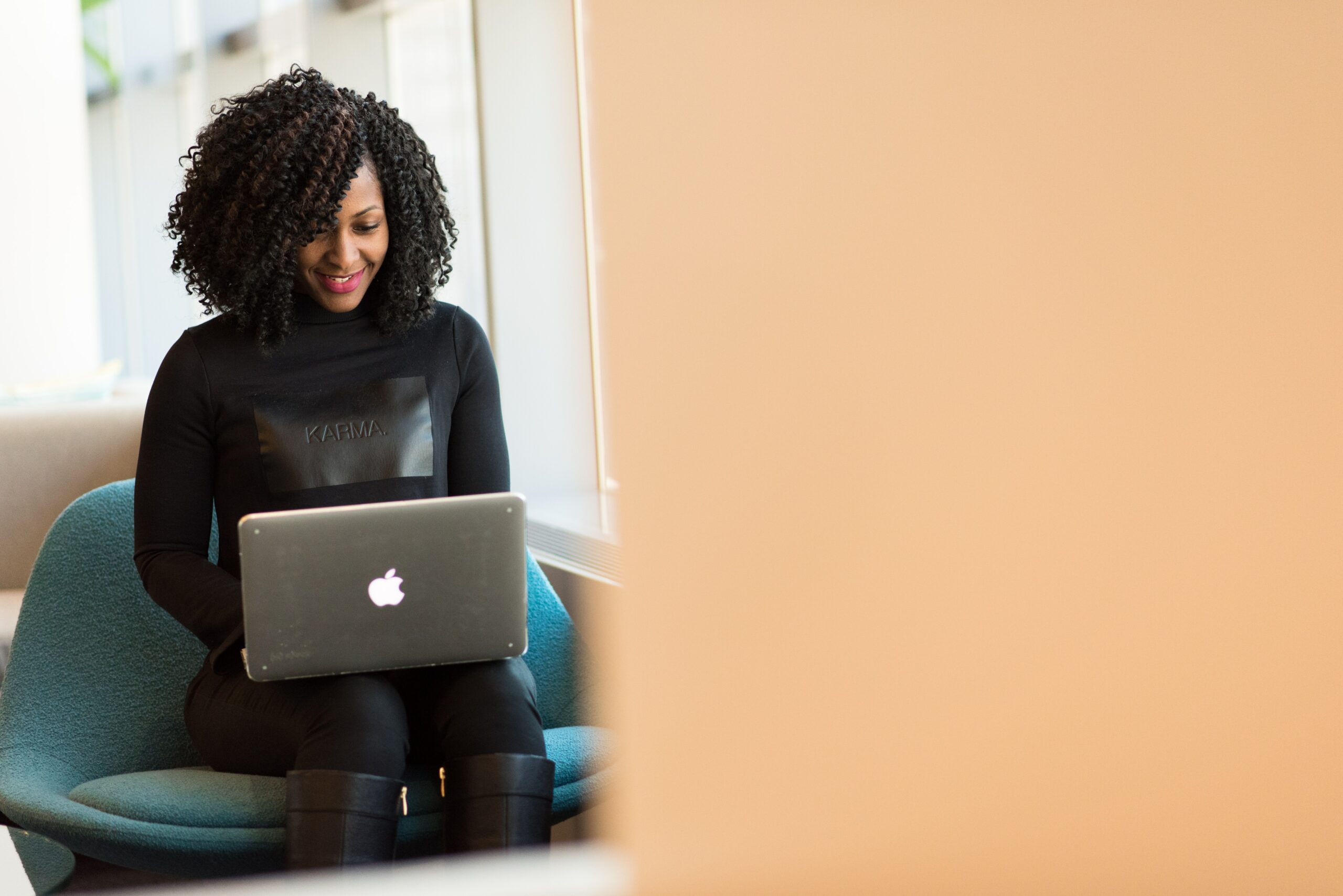 Mulher negra segurando um MacBook no ambiente de trabalho